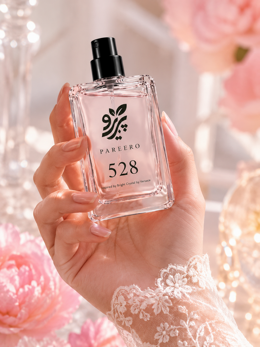 Hand holding PAREERO 528 Bright Crystal inspired fragrance in a soft pink luxury setting