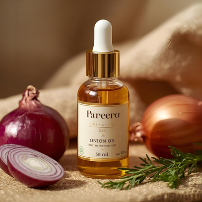 Pareero Onion Oil bottle surrounded by fresh red onions and green herbs – organic hair oil for strong and healthy hair