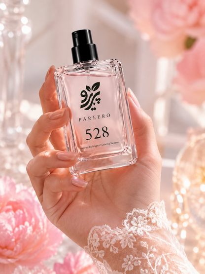 Hand holding PAREERO 528 Bright Crystal inspired fragrance in a soft pink luxury setting