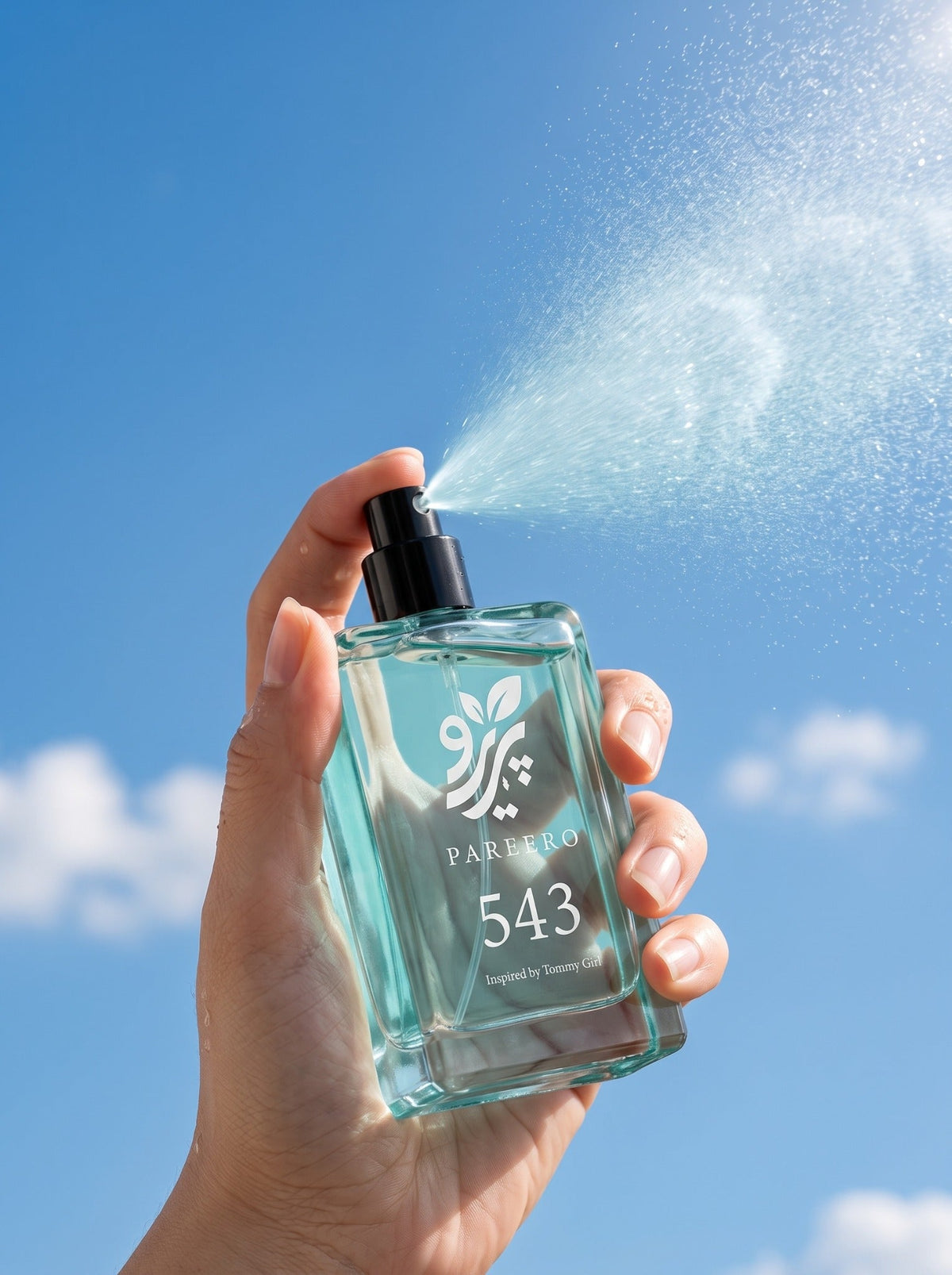 Hand spraying PAREERO 543 Tommy Girl-inspired fragrance against a bright blue sky