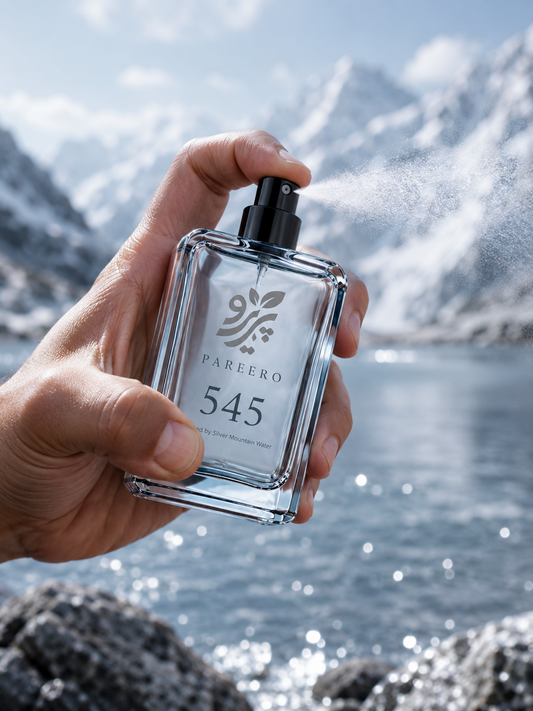 PAREERO 545 Silver Mountain Water inspired fragrance held and sprayed beside a bright alpine lake